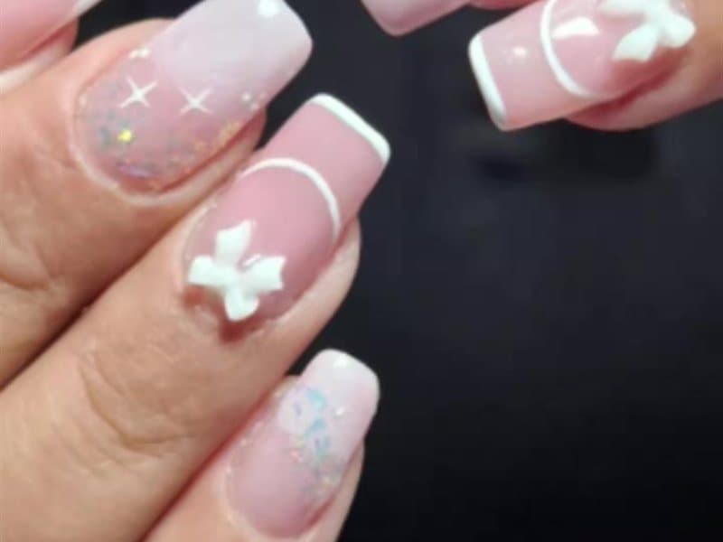 Uñas rosadas con moños y detalles en blanco